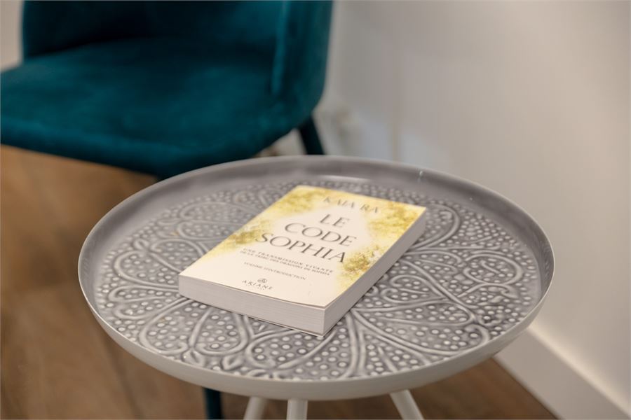 Un livre posé sur une table basse près d'un fauteuil, dans l'espace d'attente