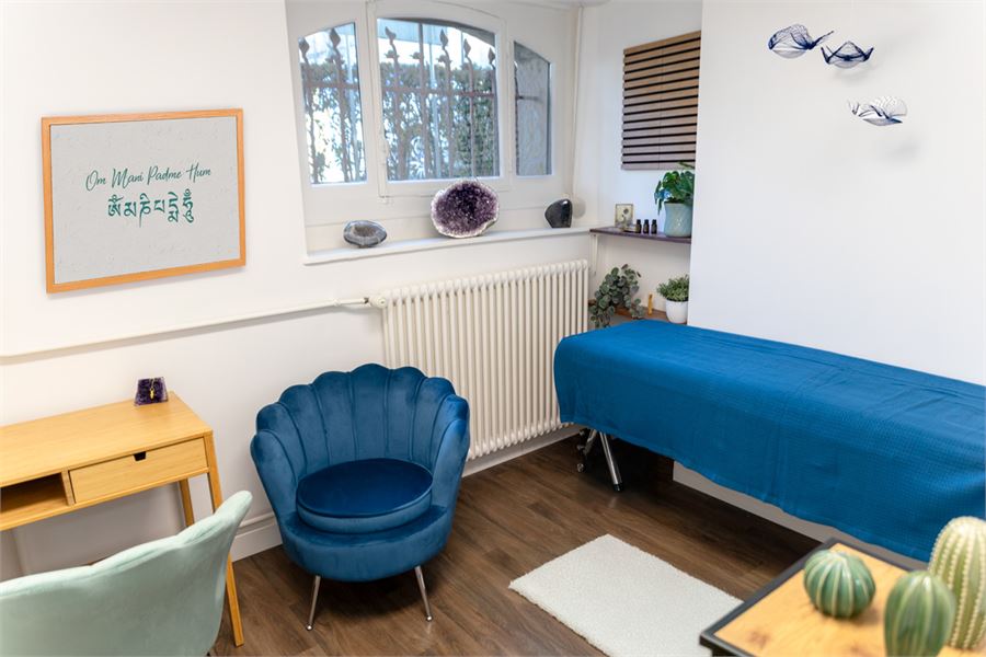 Salle Océan : la table de massage, le fauteuil bleu et le mantra encadré